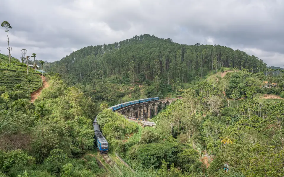 A blue train crossing Nine Arches Bridge near Ella